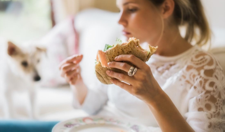 woman-experiencing-compulsive-eating-before-period-holding-a-sandwich.jpg